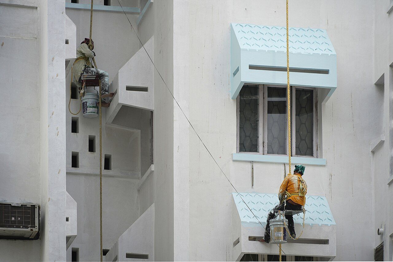 Maler arbeiten abgeseilt an einer Hausfassade