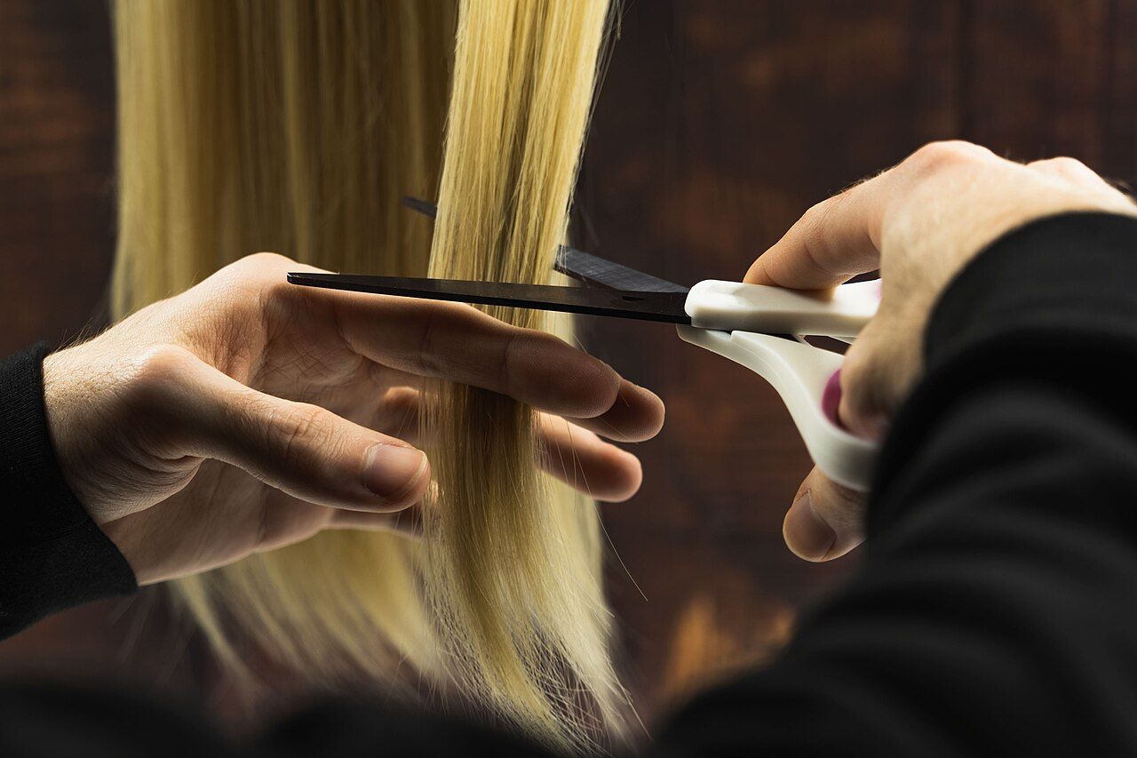 Hände schneiden mit der Schere eine Haarsträhne