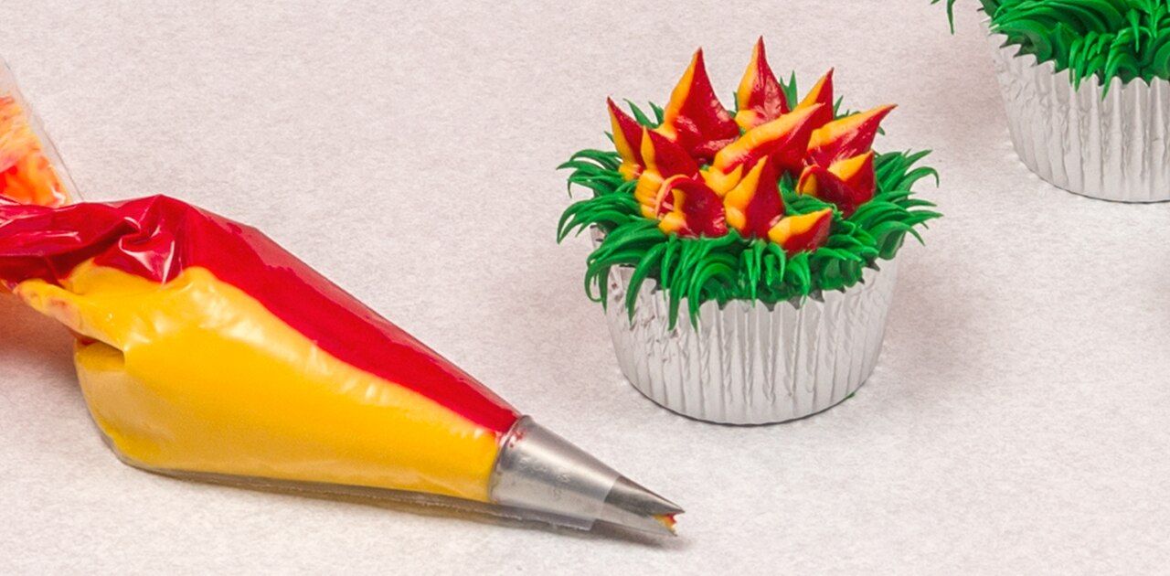 Spritzbeutel neben verzierten Cupcakes
