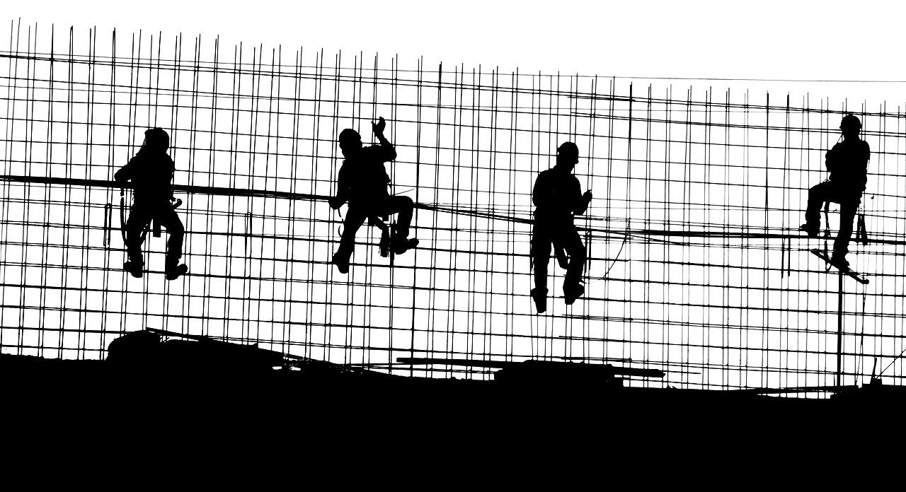 Bauarbeiter als Silhouetten auf einer Bewehrung