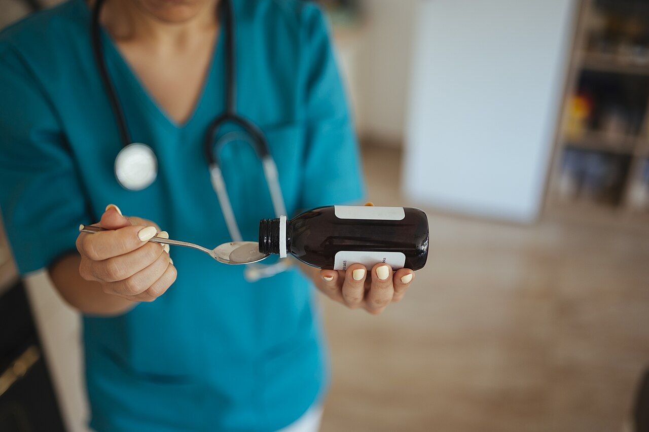 Pflegekraft gibt Medizin mit einem Löffel