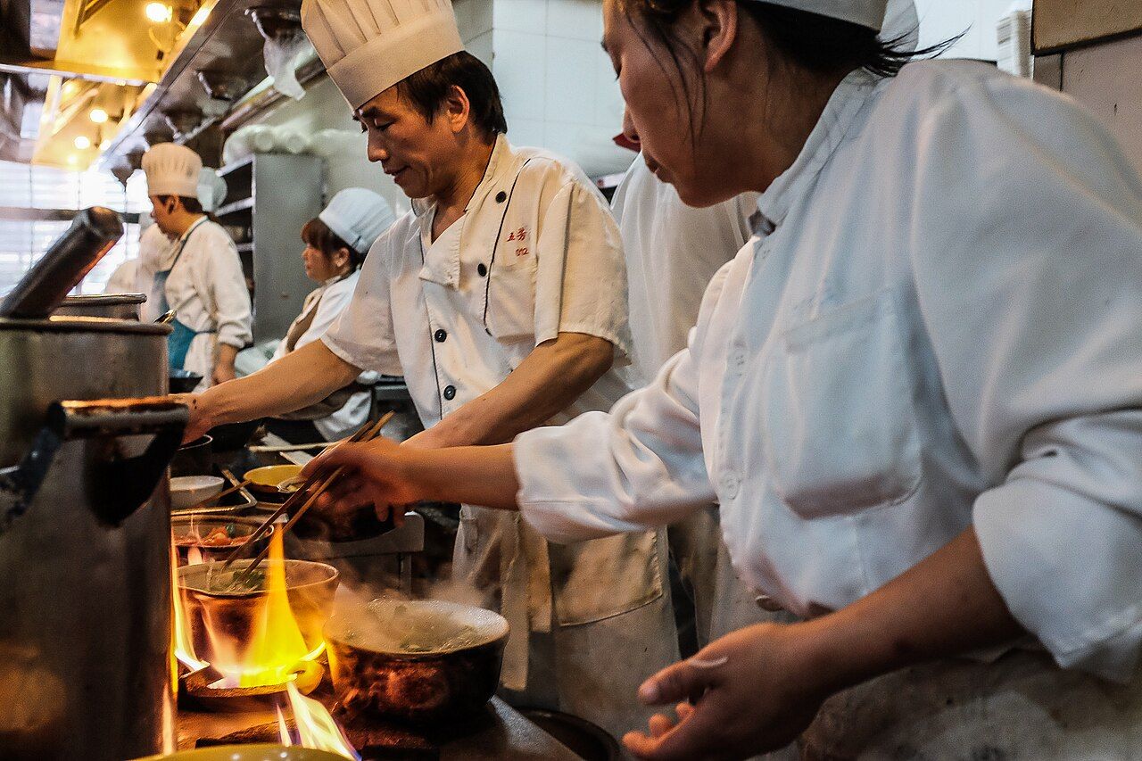 Köche an den Herdflammen einer Restaurantküche