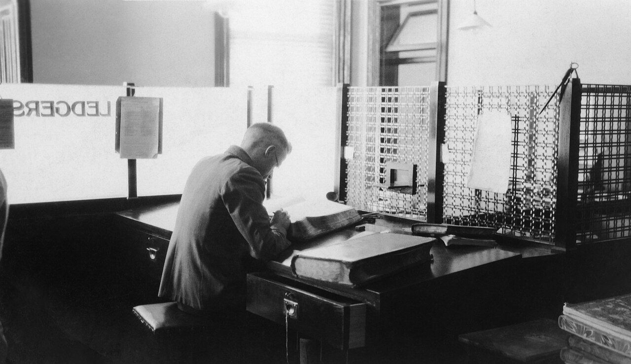 Bankangestellter am Schreibtisch mit Hauptbuch, historische Aufnahme