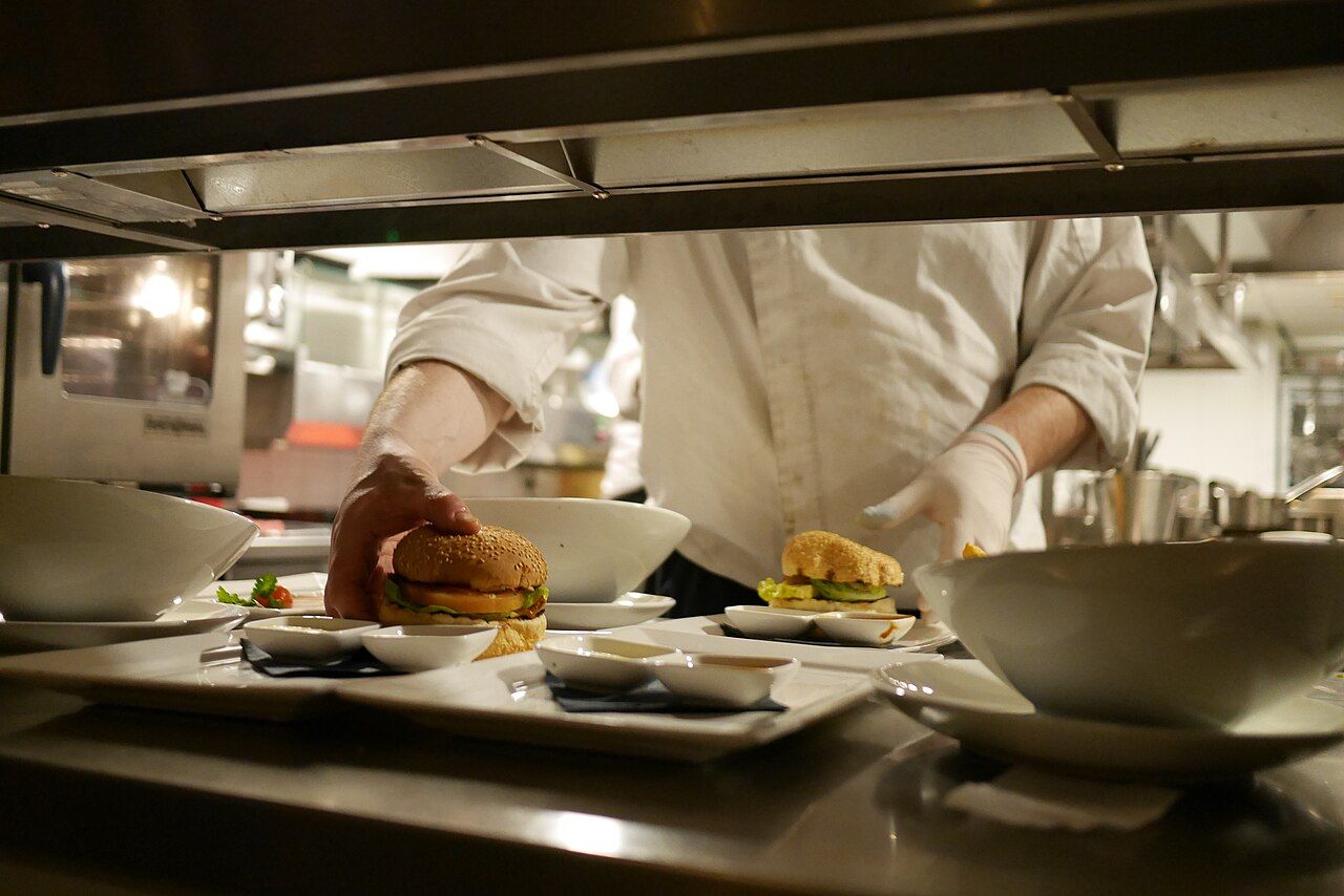 Hände richten Burger auf Tellern an