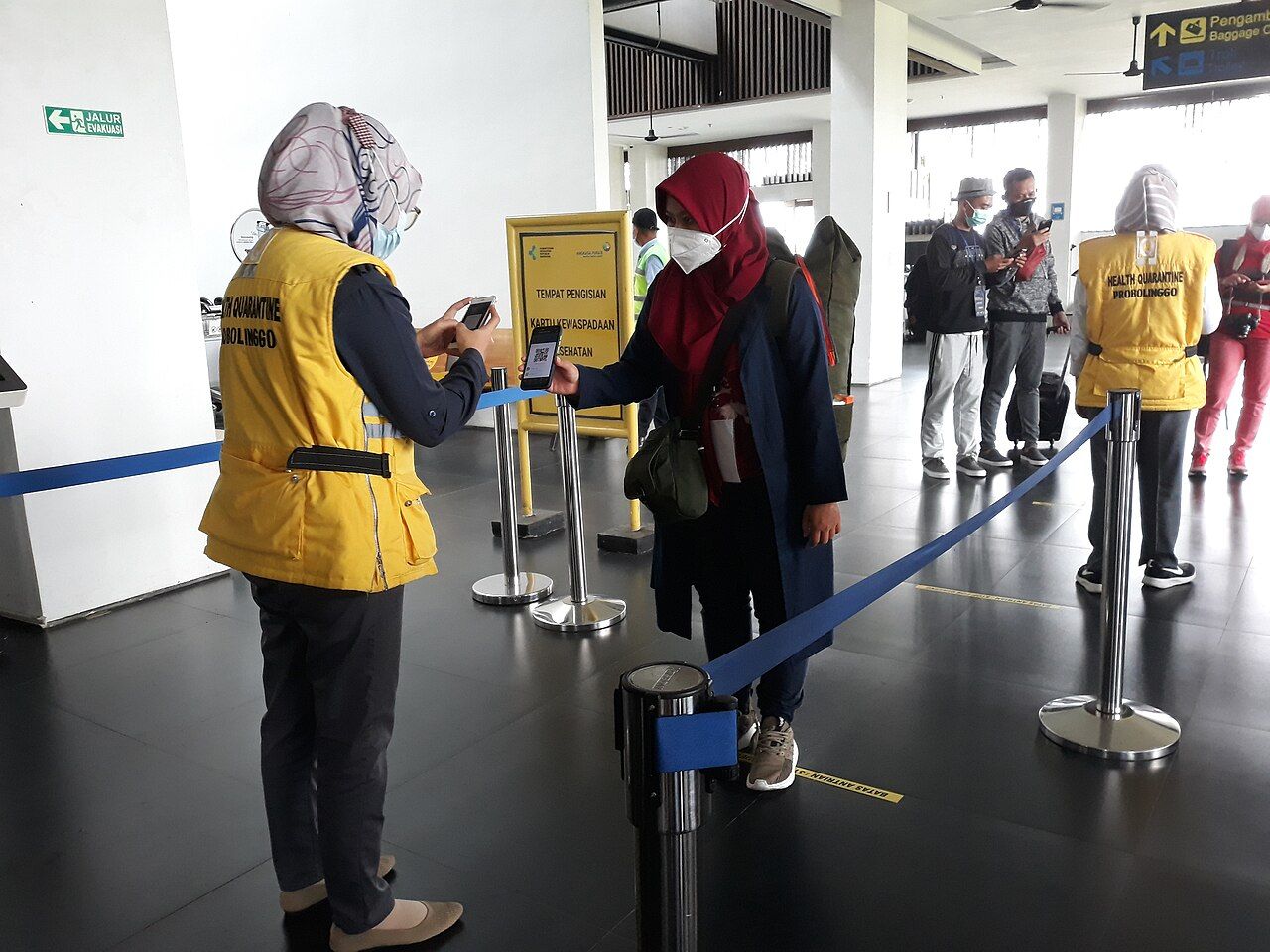 Sicherheitspersonal kontrolliert Fluggäste an einer Absperrung