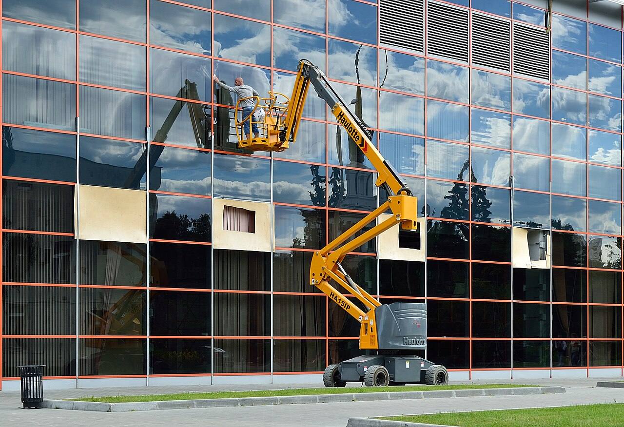 Fensterreiniger auf einer Hubarbeitsbühne an einer Glasfassade
