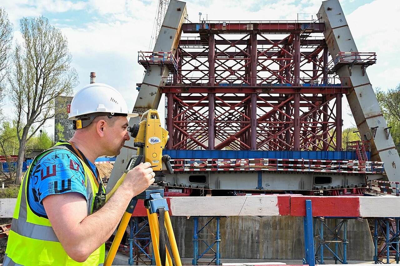 Vermessungstechniker mit Theodolit an einer Brückenbaustelle