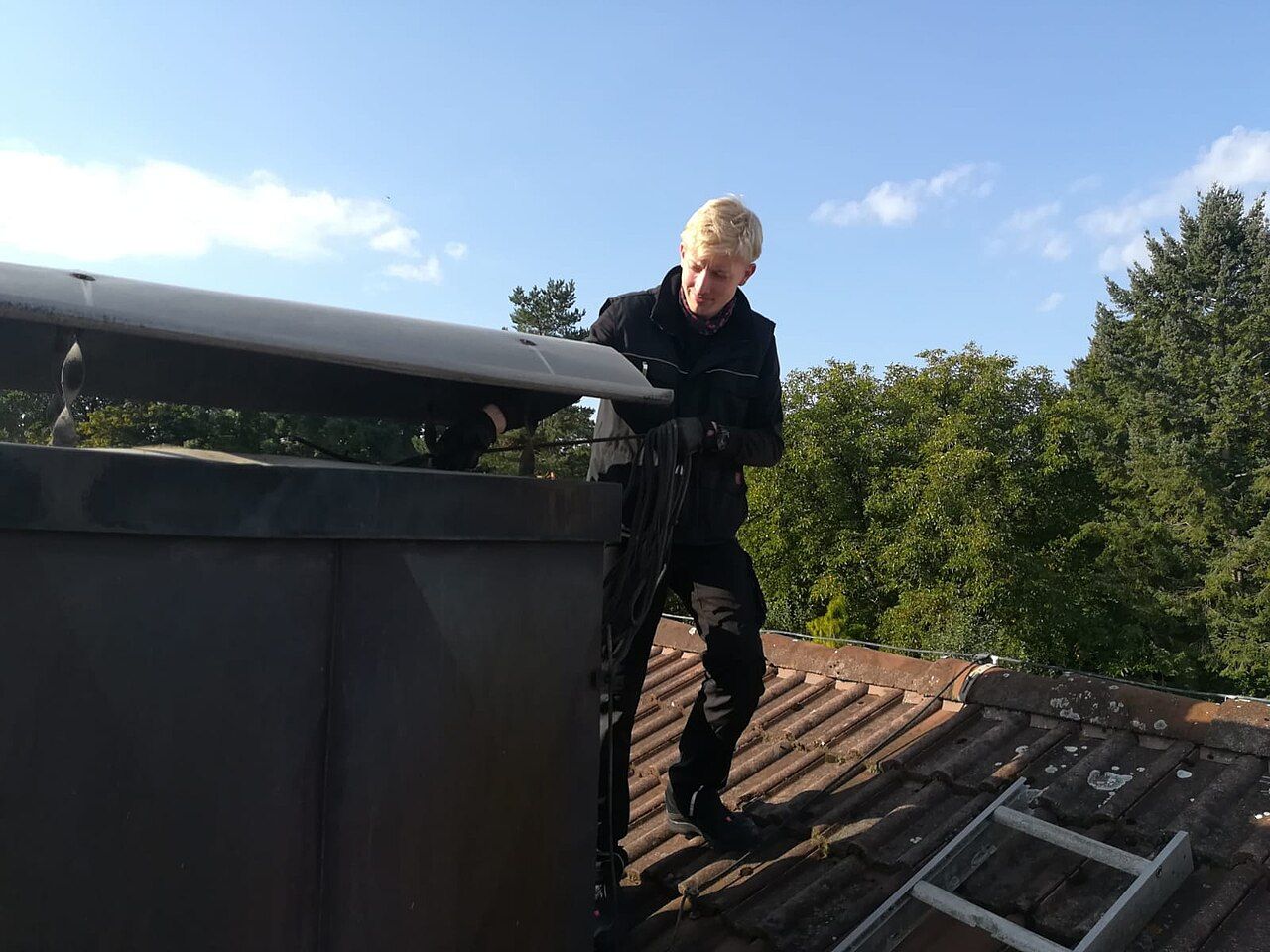 Schornsteinfeger-Auszubildender auf einem Dach