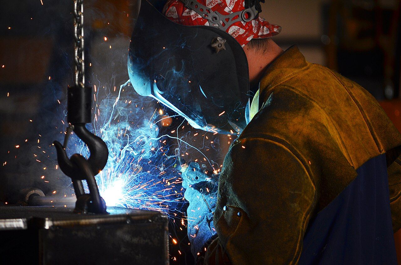 Schweißer mit Helm und Funkenflug an einem Werkstück