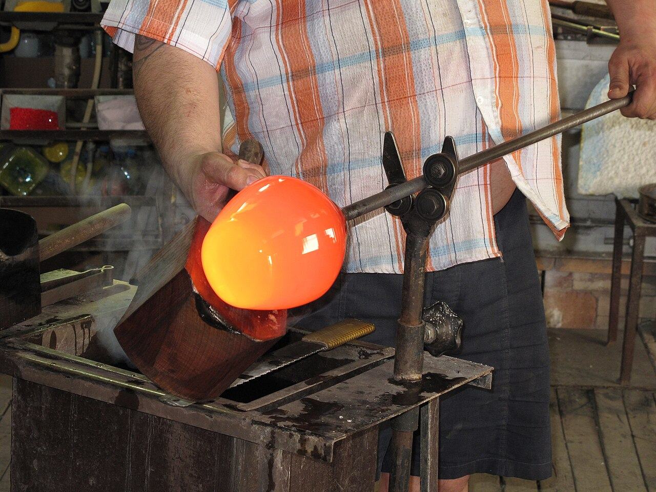 Glasbläser formt glühendes Glas an der Glasmacherpfeife