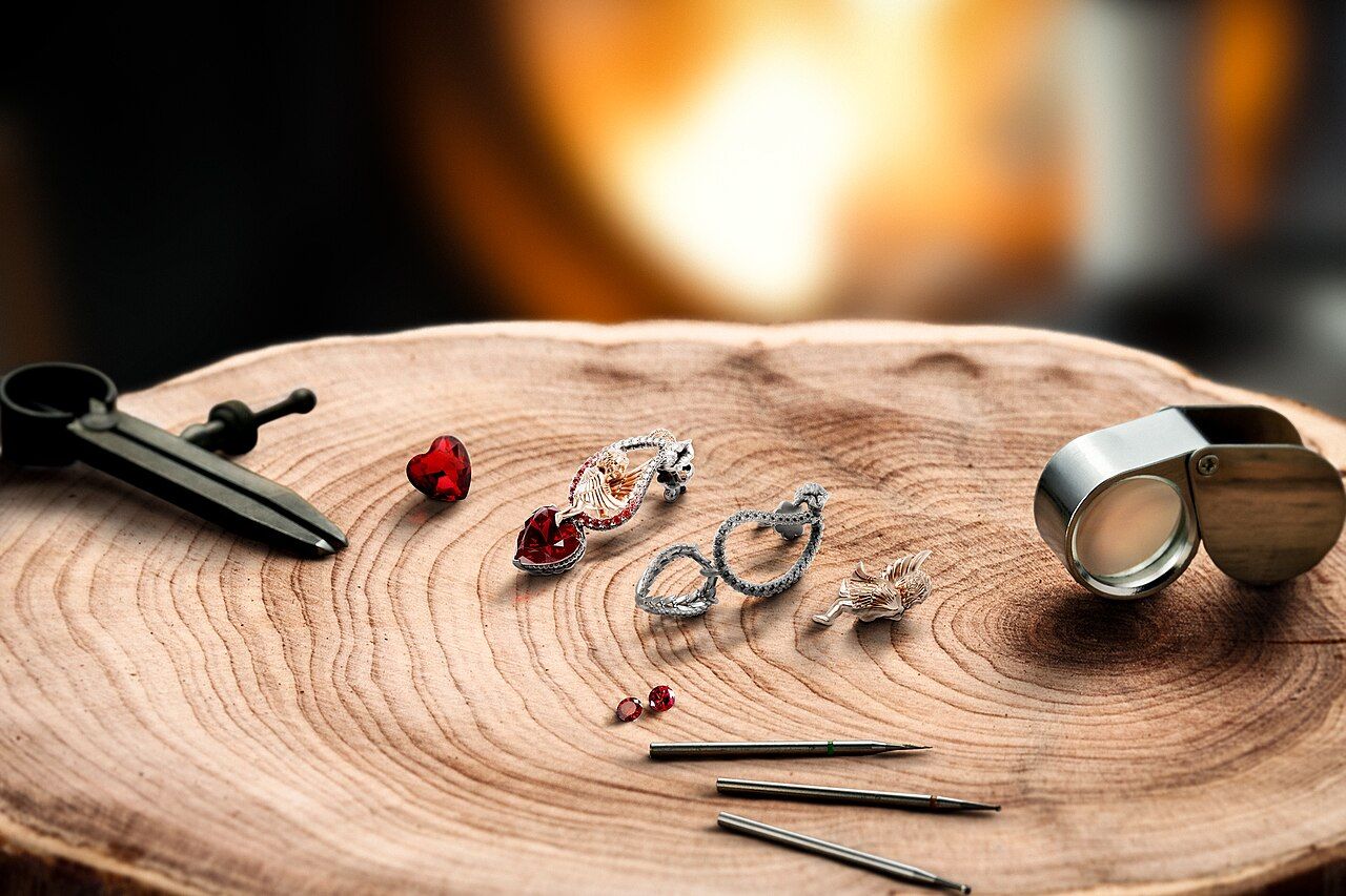 Schmuckwerkzeuge, Ringe und Lupe auf einer Holzscheibe