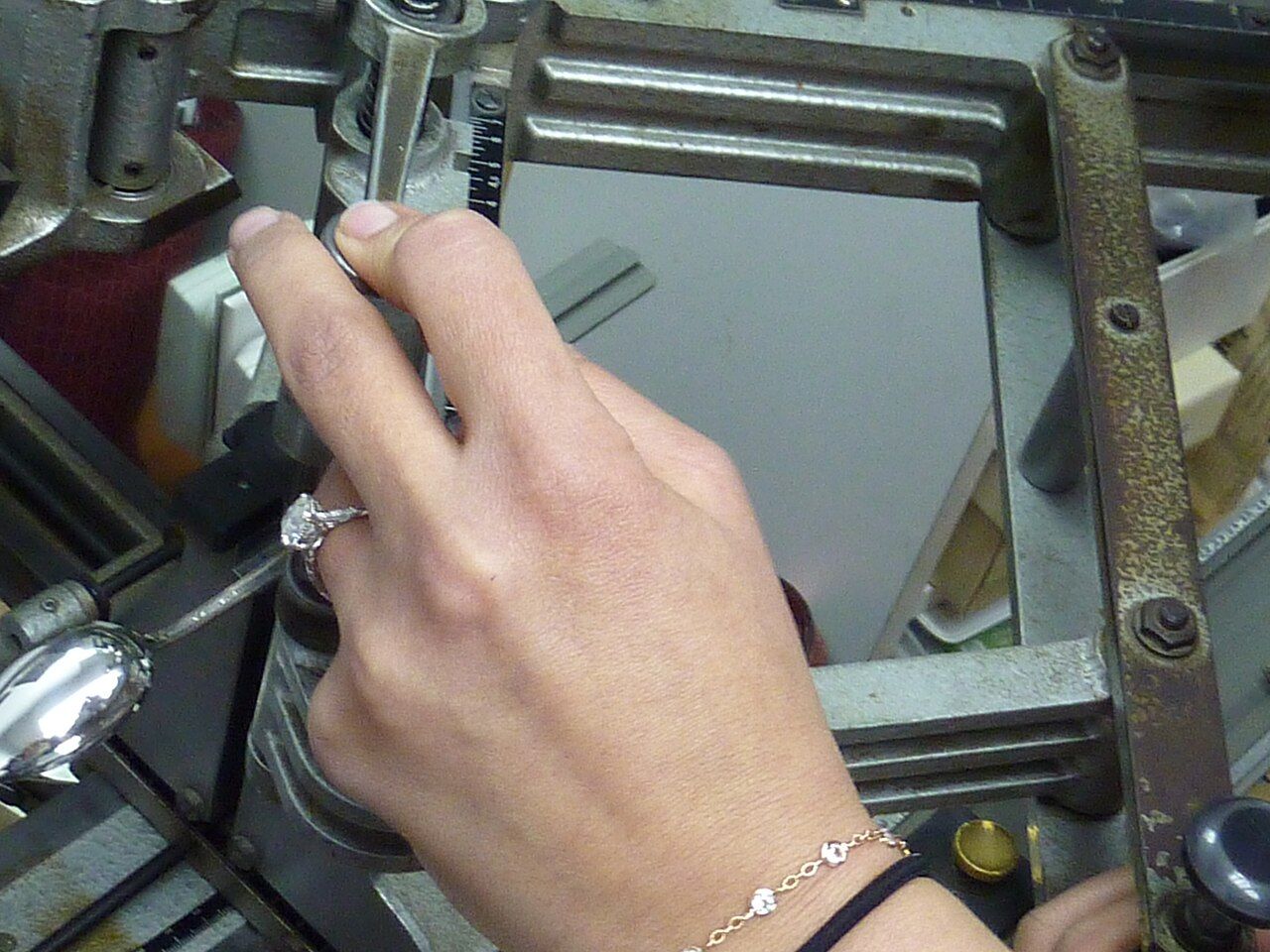 Hand führt ein Werkstück an einer Graviermaschine