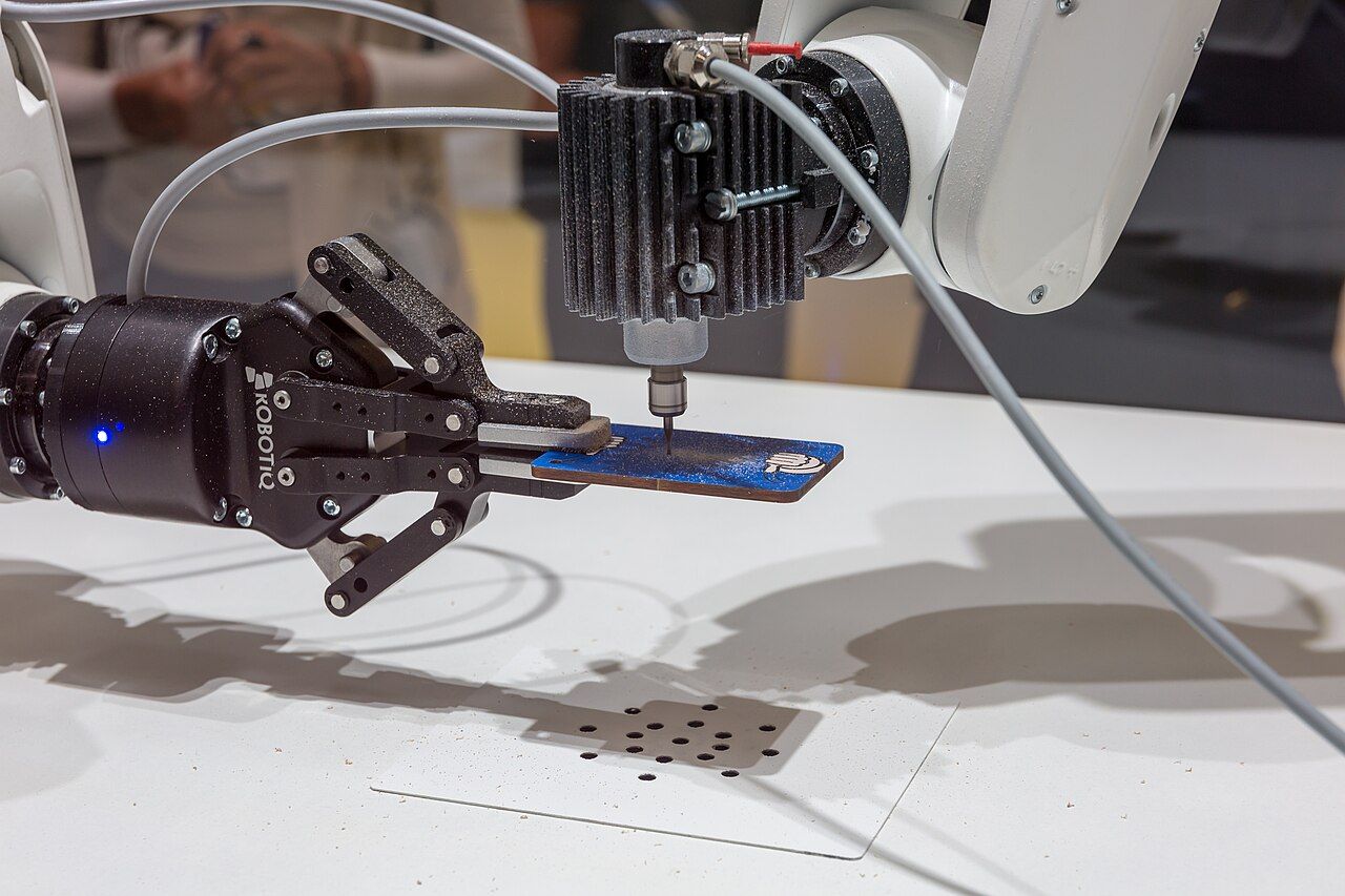 Roboterarm mit Greifer hält eine Platine