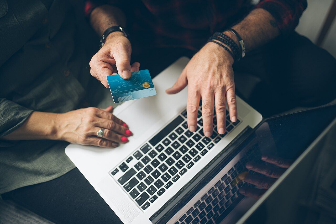 Hände tippen auf einem Laptop und halten eine Bankkarte