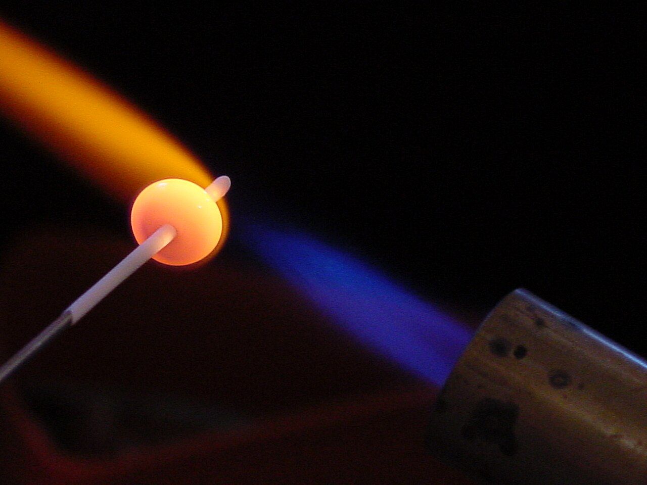 Glühende Glasperle an einem Stab in der Flamme