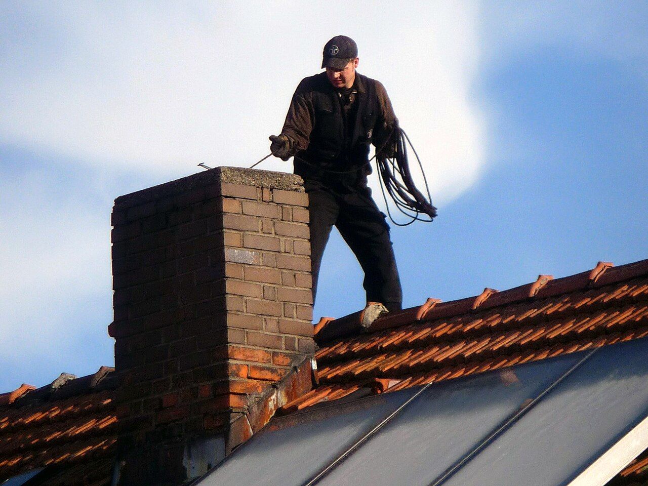 Schornsteinfeger steht mit Seil auf einem Schornstein