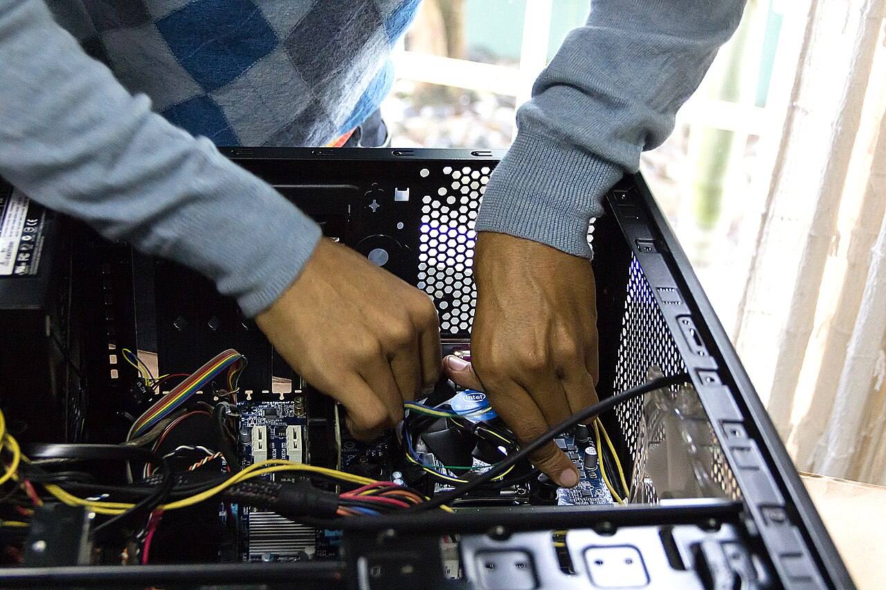 Hände schrauben im geöffneten Computergehäuse