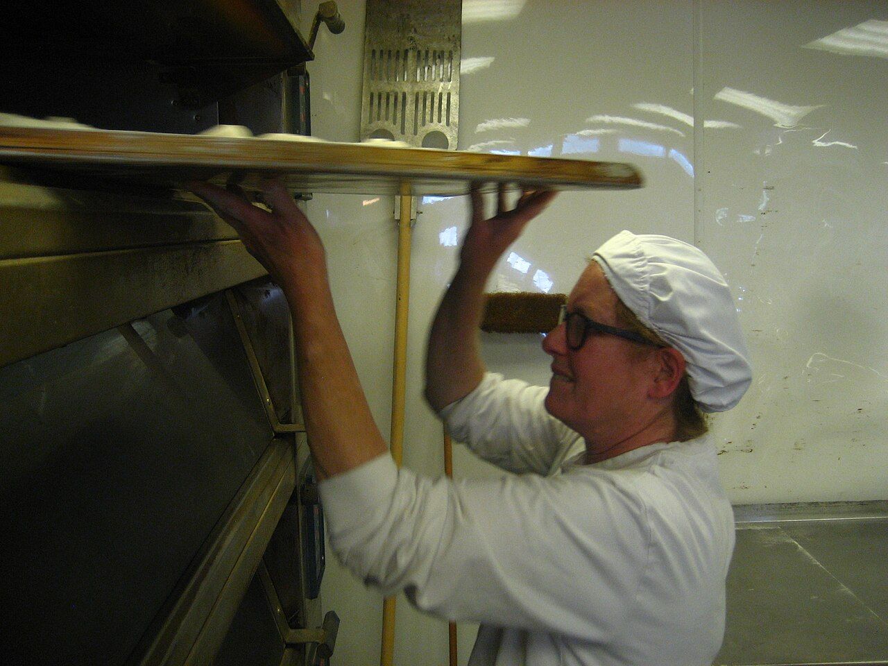 Bäckerin schiebt Brot in den Backofen