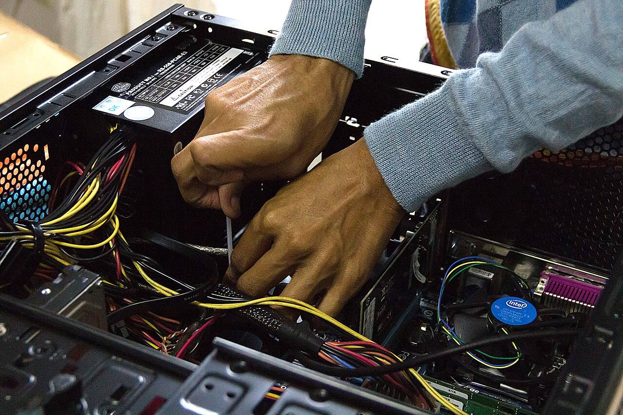 Hände arbeiten an der Verkabelung im Computergehäuse