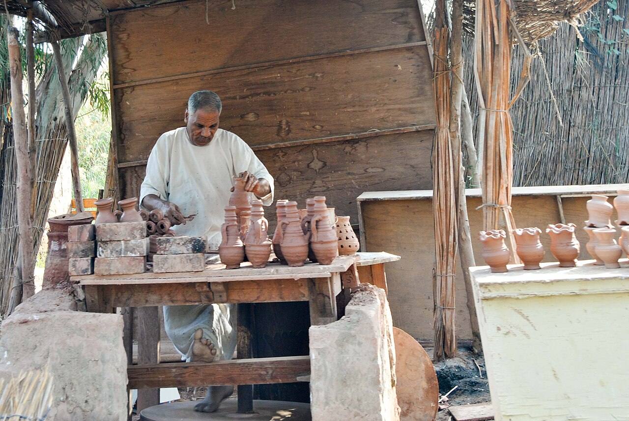Töpfer an einem Tisch mit Tongefäßen