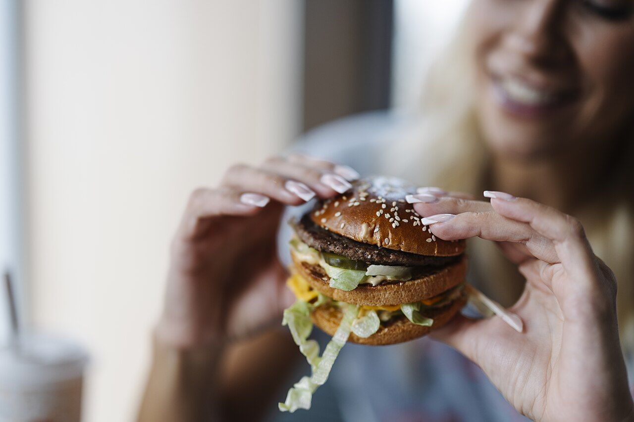 Hände halten einen Burger in einem Schnellrestaurant