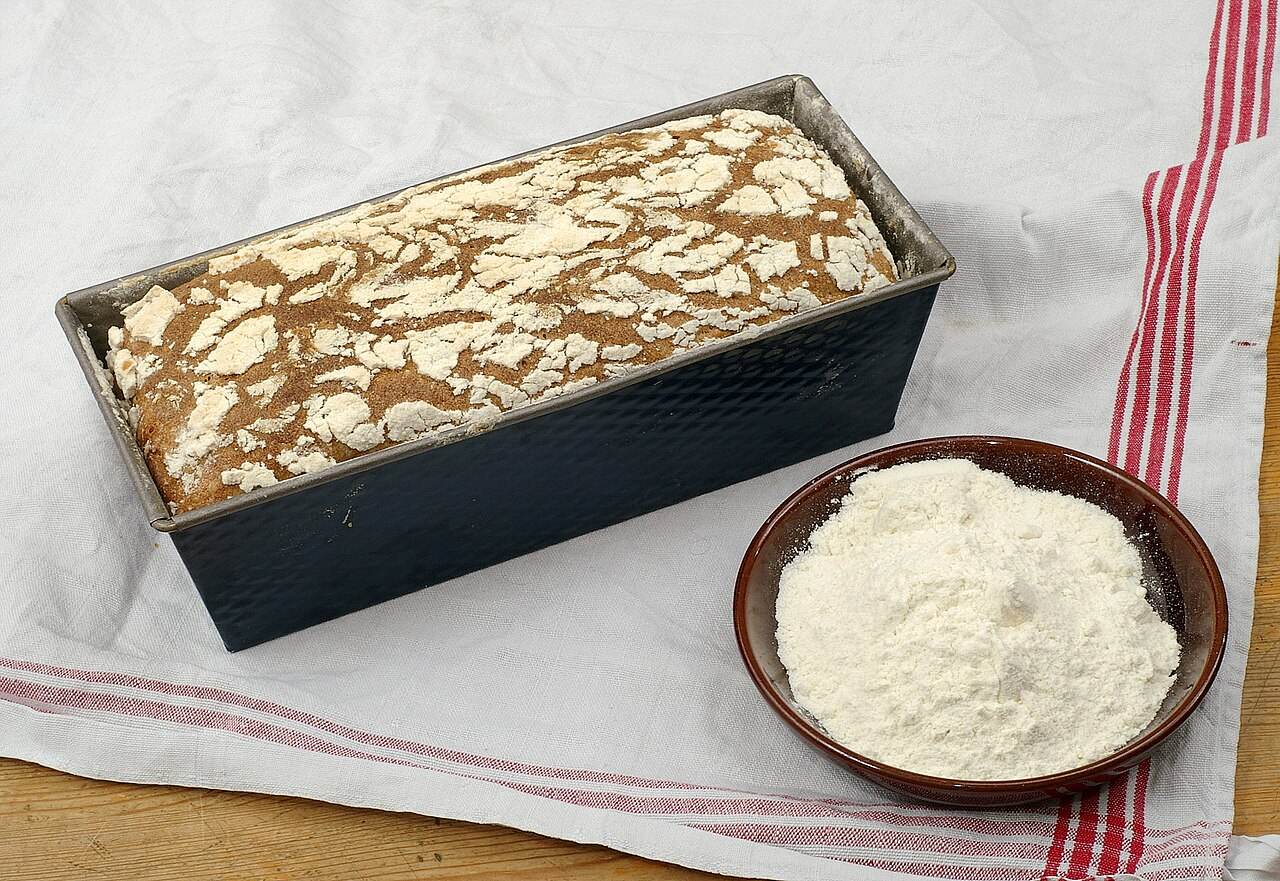 Brot in der Kastenform neben einer Schale Mehl