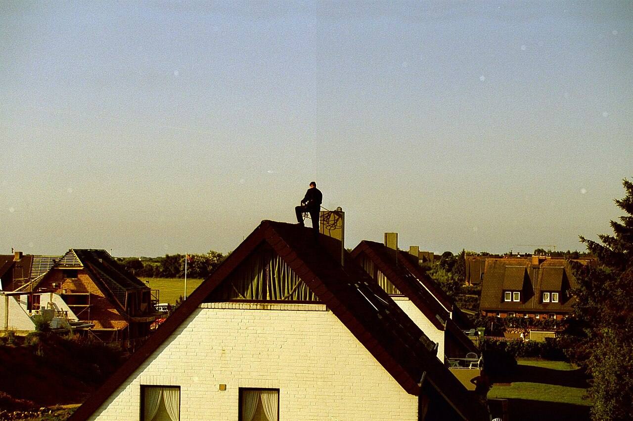 Schornsteinfeger auf einem Hausdach in der Abenddämmerung