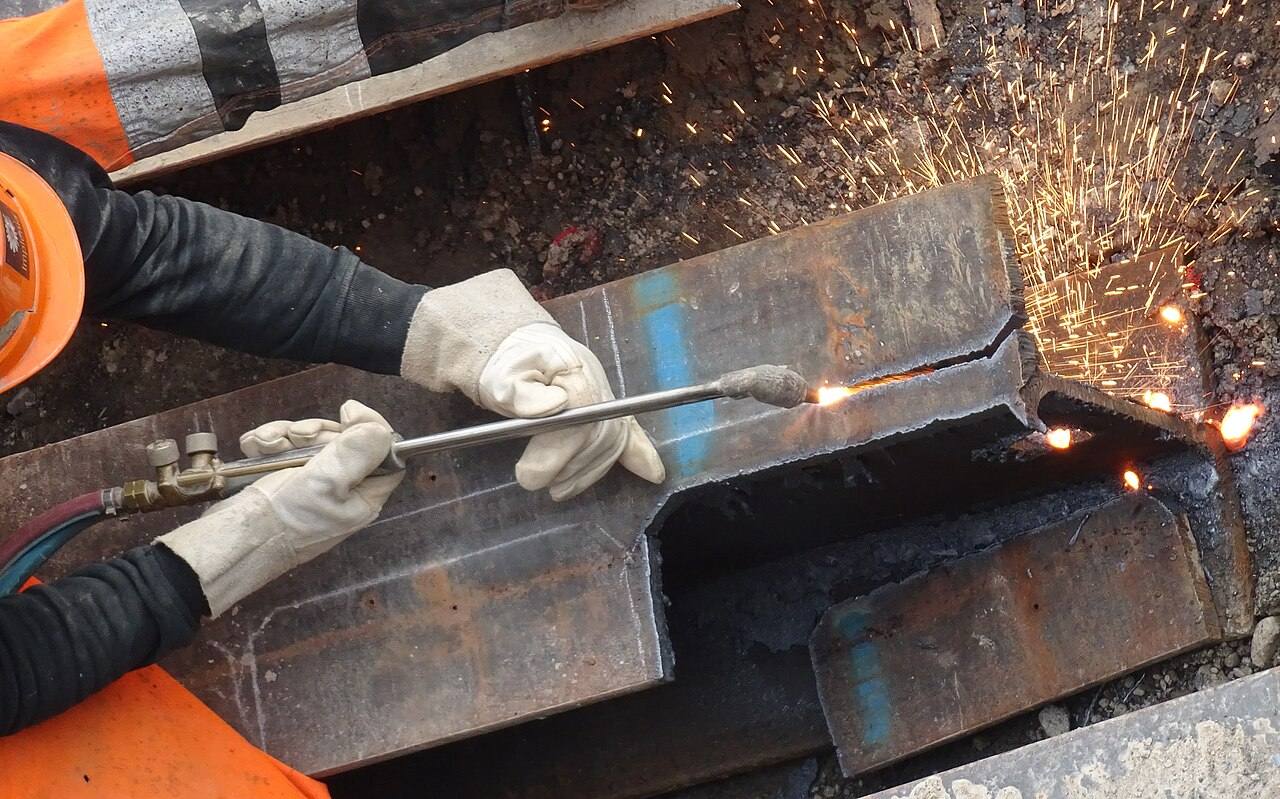 Hände mit Schutzhandschuhen schneiden Stahl mit dem Brenner