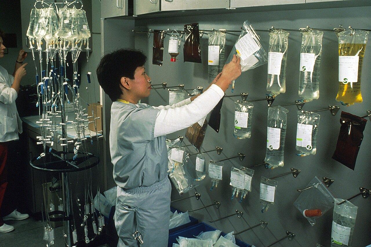 Pflegekraft hängt Infusionsbeutel an eine Wand