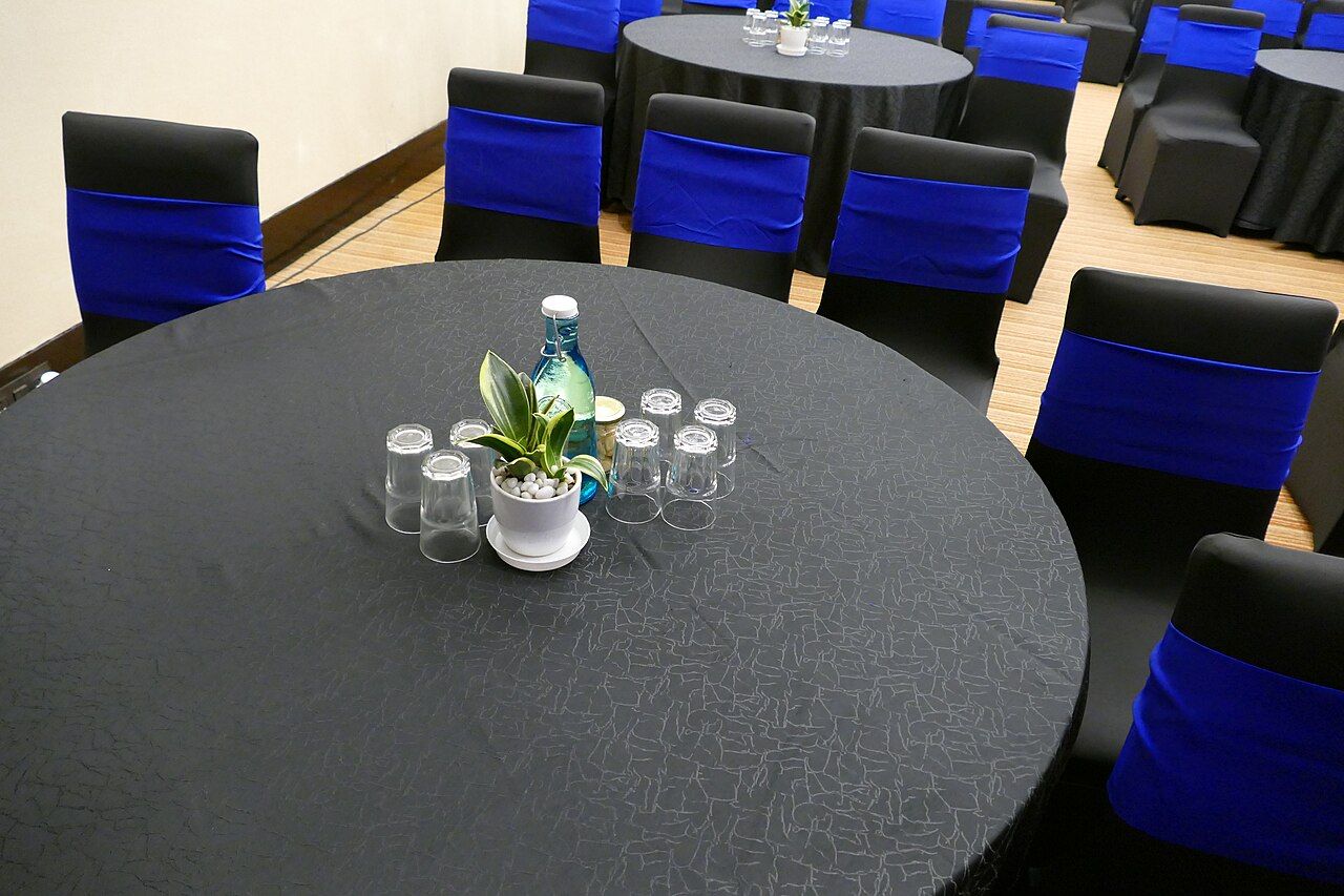 Runder Tisch mit Gläsern und Blumenschmuck in einem Tagungsraum
