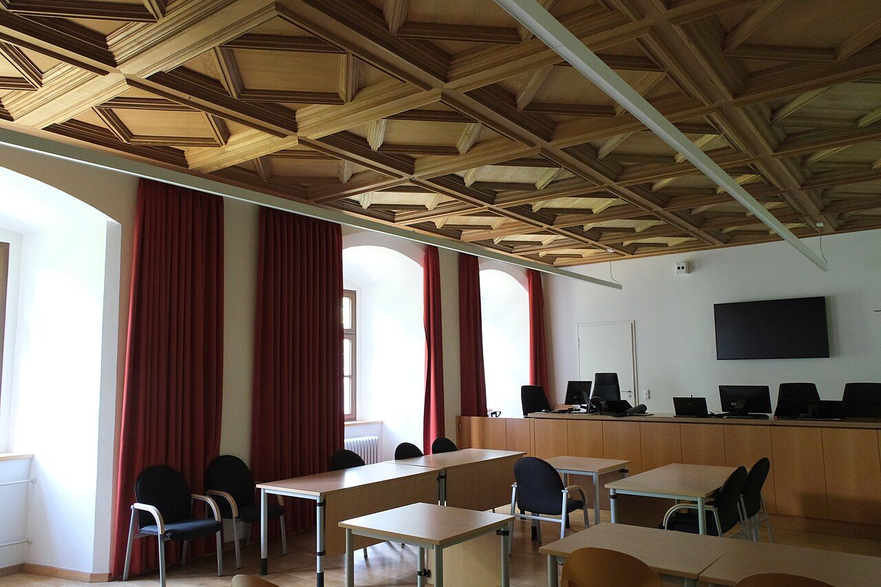 Gerichtssaal mit Kassettendecke und roten Vorhängen