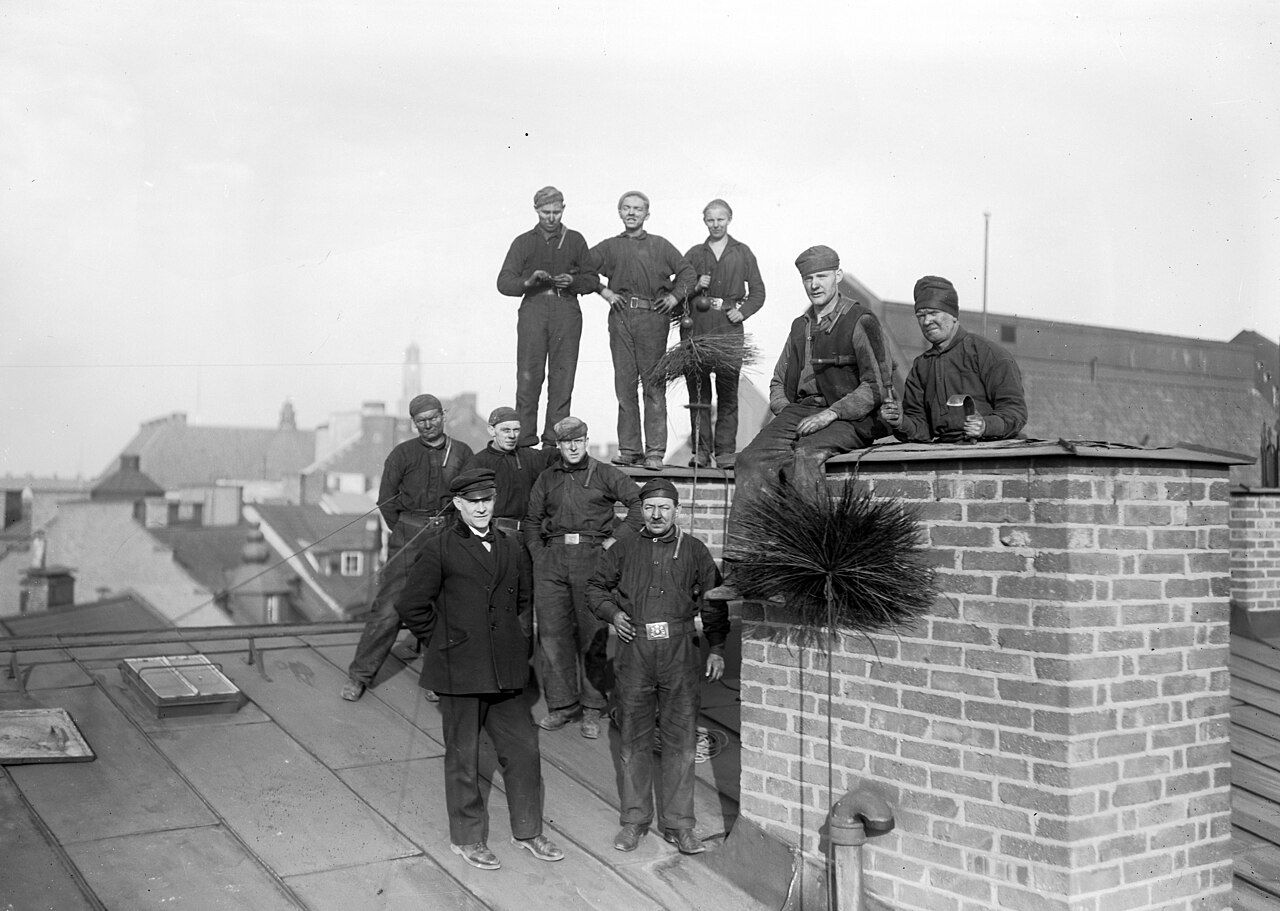 Schornsteinfeger mit Kehrbesen auf einem Dach, historische Aufnahme