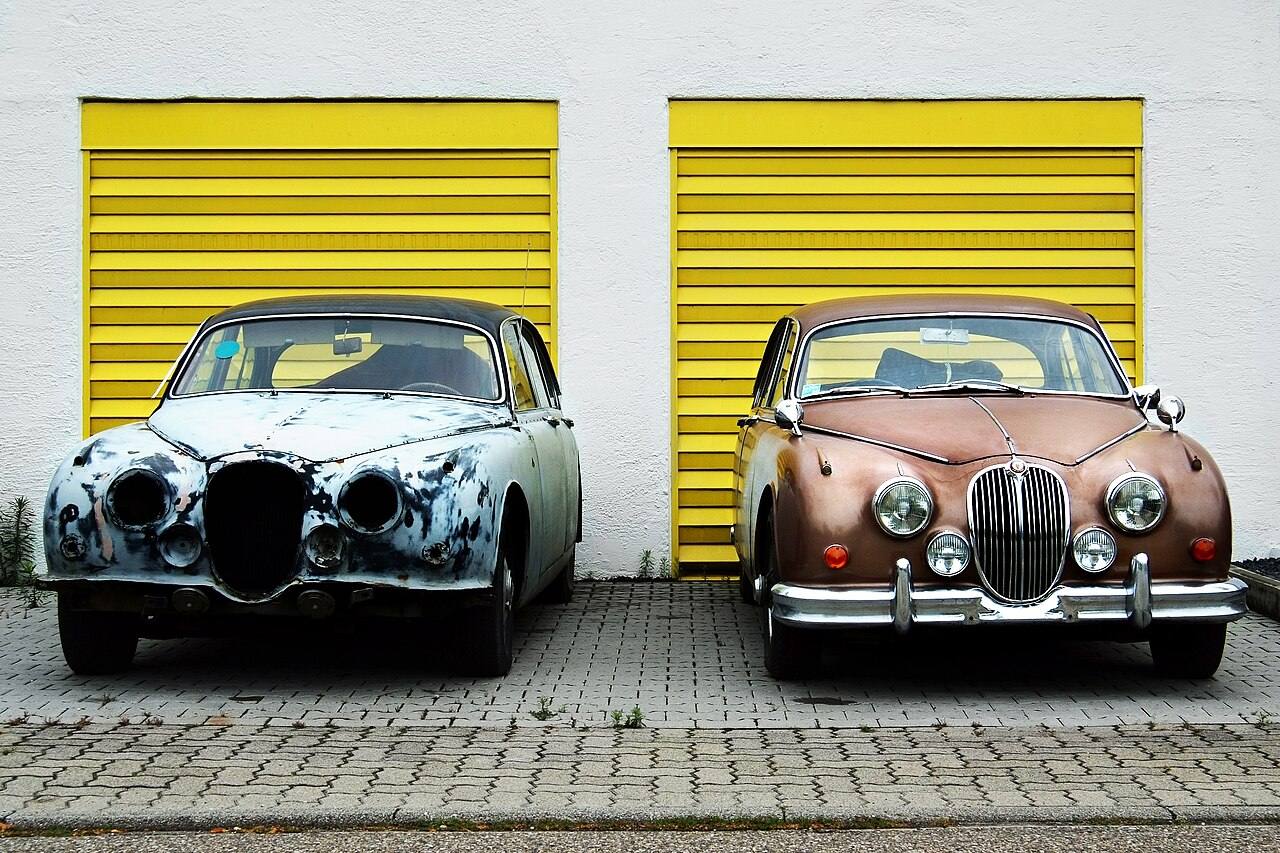 Zwei Oldtimer vor Werkstatttoren, Karosserie vor und nach der Lackierung