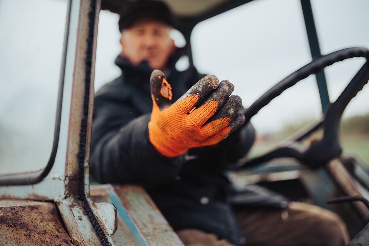 Behandschuhte Hand eines Landwirts am Traktorlenkrad