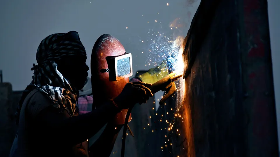 Schweisser mit Schutzhelm bei Schweissarbeiten an einem Metallteil