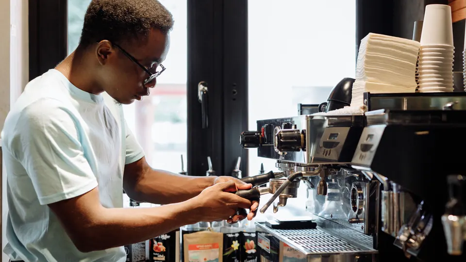Junger Barista bedient eine Espressomaschine in einem Café