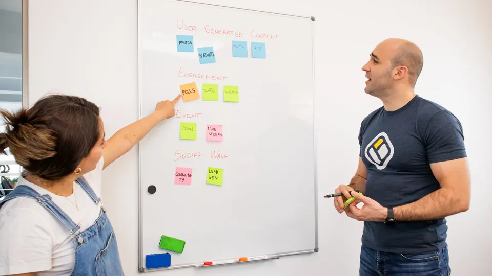 Zwei Personen planen Arbeitsschritte mit Haftnotizen an einem Whiteboard