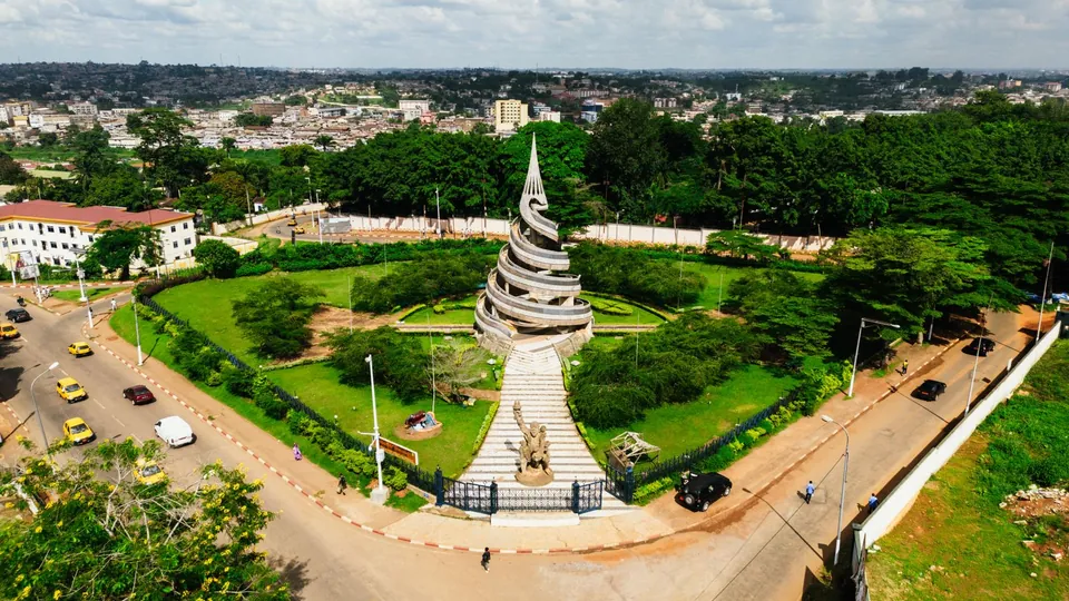 Luftaufnahme des Wiedervereinigungsdenkmals in Yaoundé mit Grünanlage und Straßenverkehr, Kamerun.