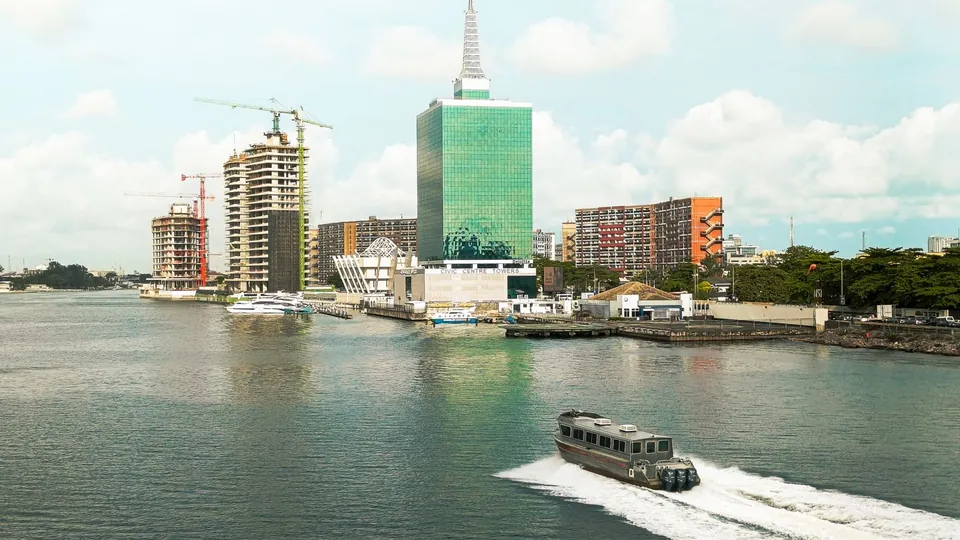 Skyline von Lagos mit Hochhäusern am Ufer der Lagune und einem Boot im Vordergrund, Nigeria.